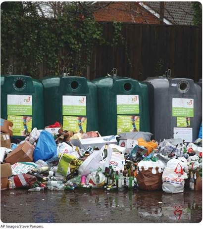A photo shows a row of four recycling bins.